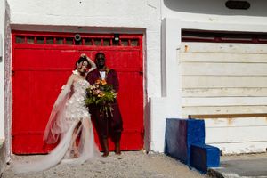 A panoramic view of a rustic white building with bright red doors and blue trim details along its exterior.