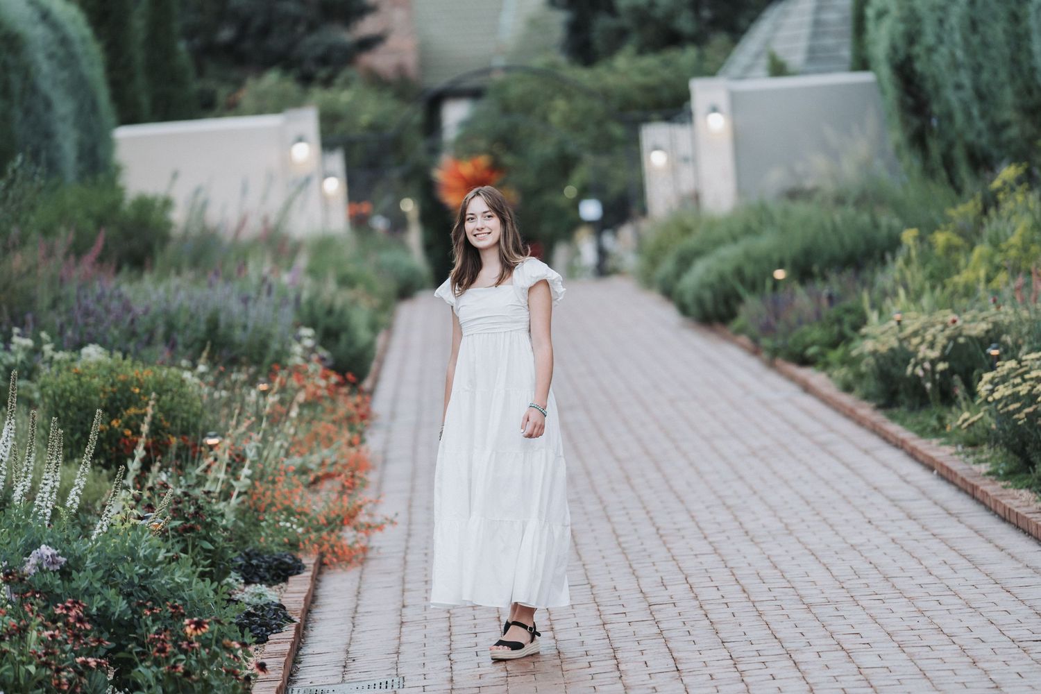 A peaceful garden walkway lined with mixed perennials and greenery.