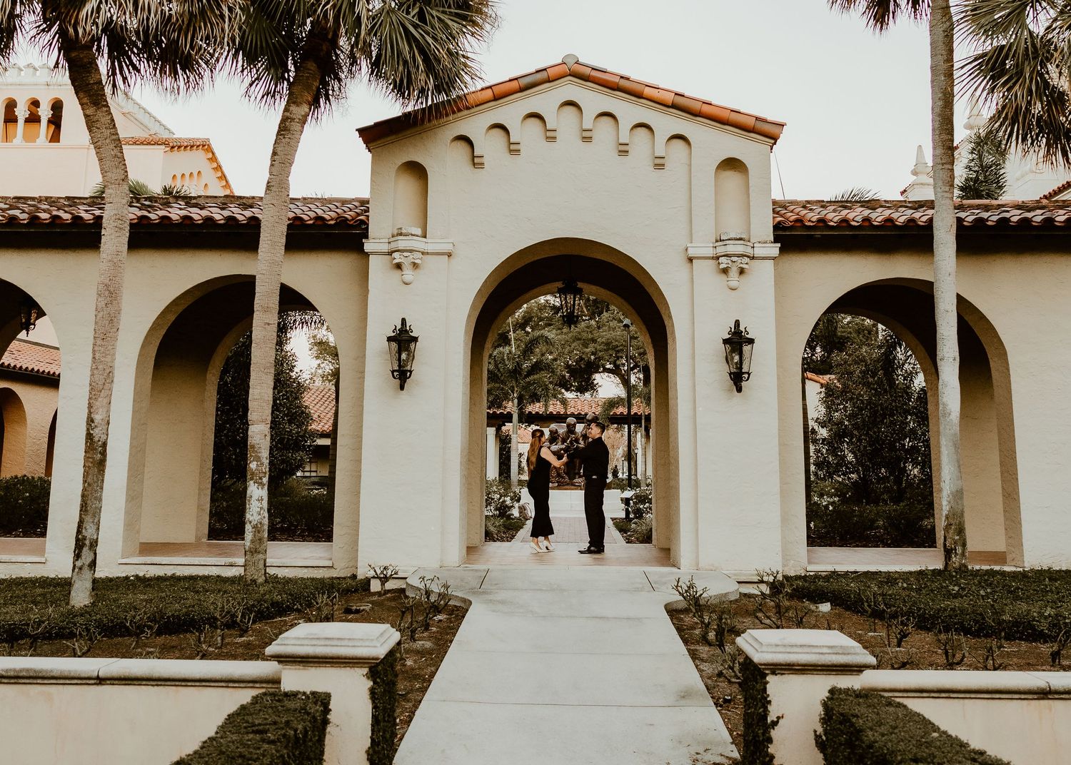 Spanish-style architecture with white stucco walls and palm trees at a wedding venue.