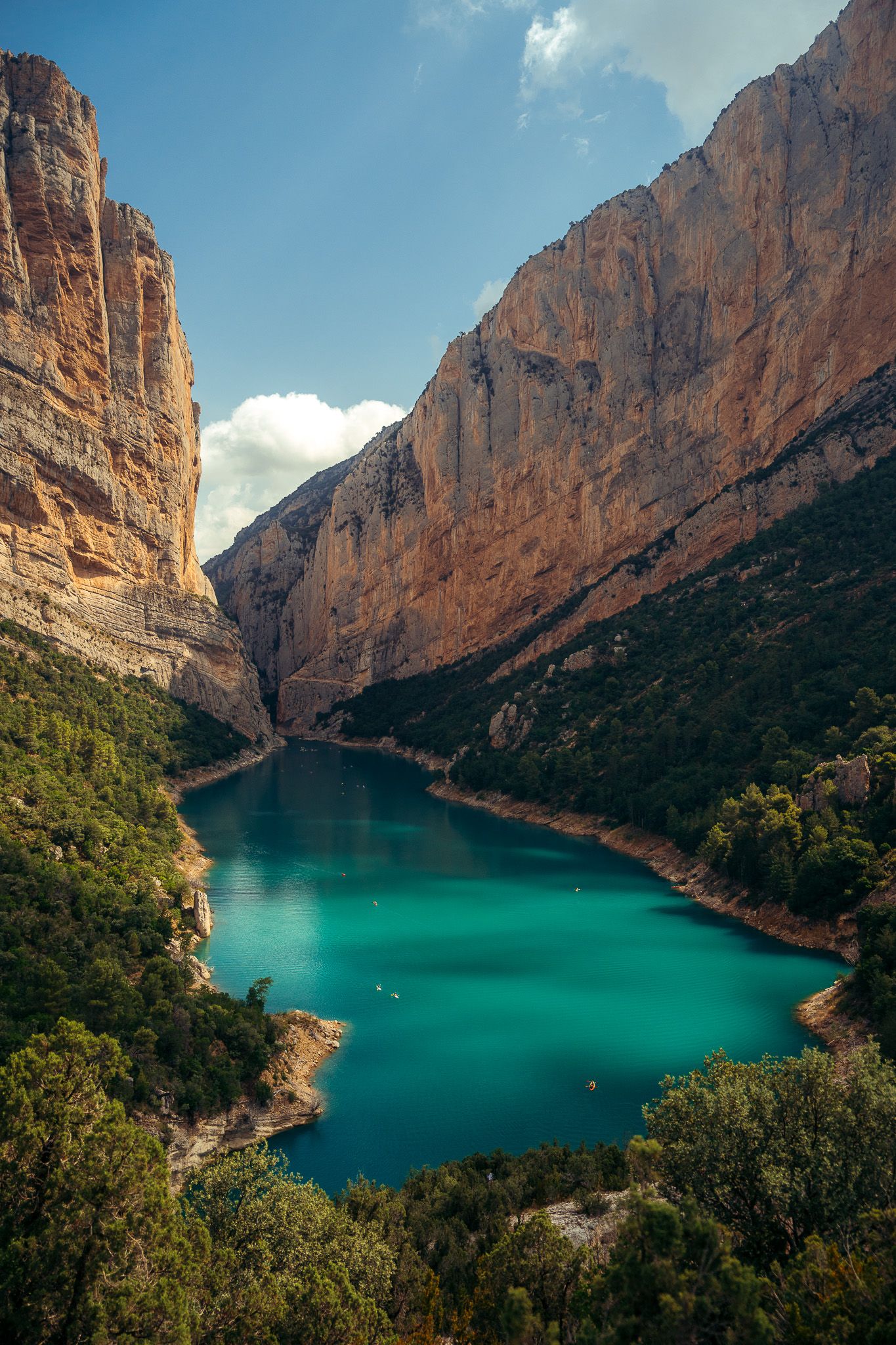 Majestic canyon walls frame a vibrant turquoise lake under clear blue skies.