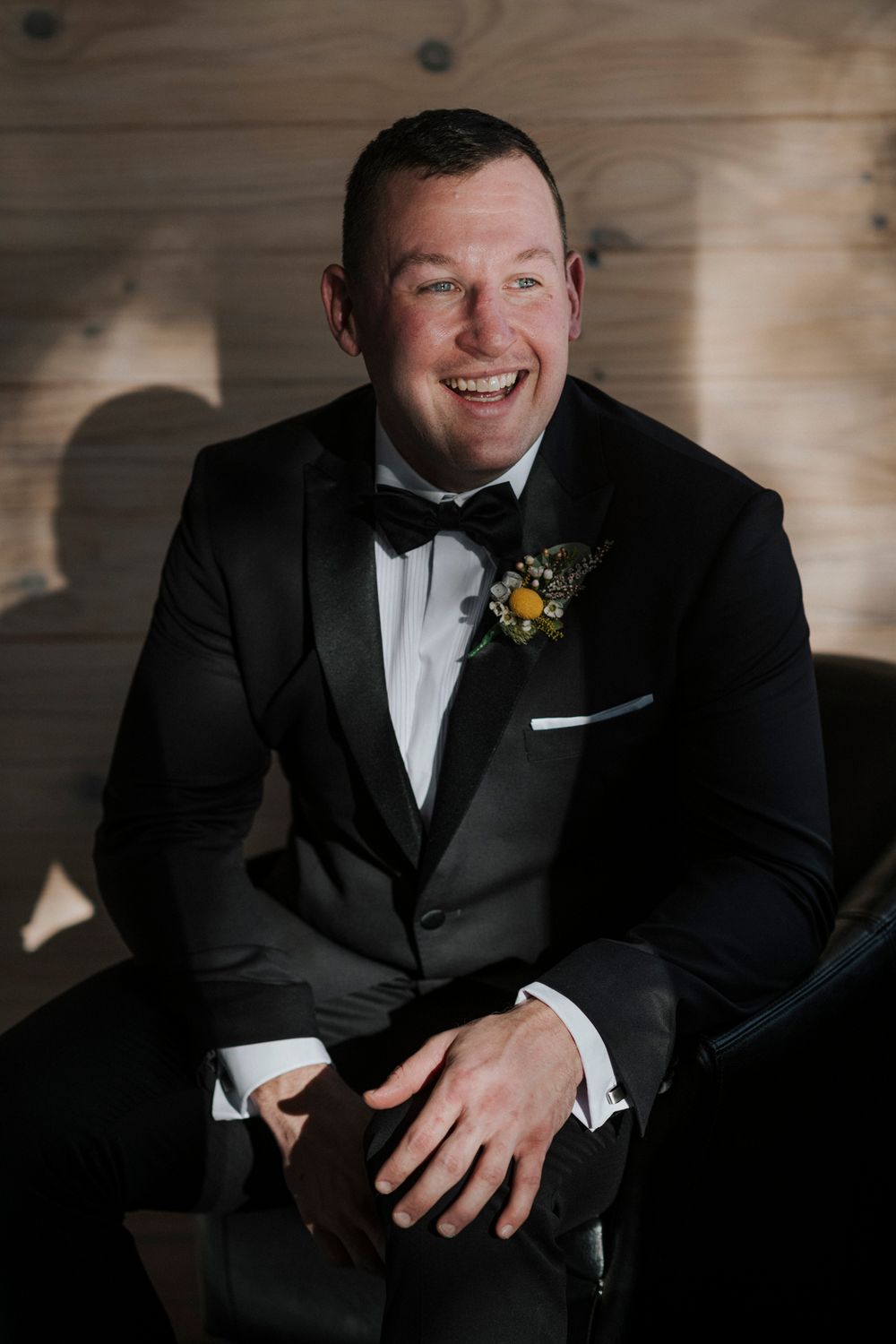 A series of five formal black and white portraits of someone wearing a tuxedo and bow tie against a rustic backdrop.
