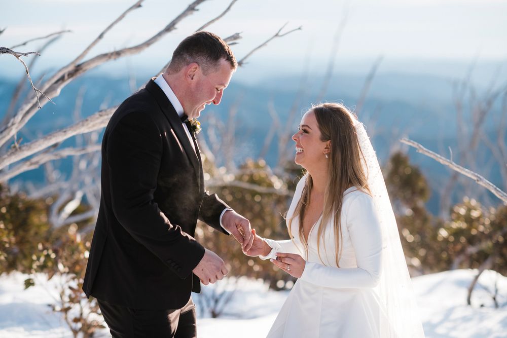 Winter wedding couple shares an intimate moment in the snowy mountain landscape during their outdoor ceremony.