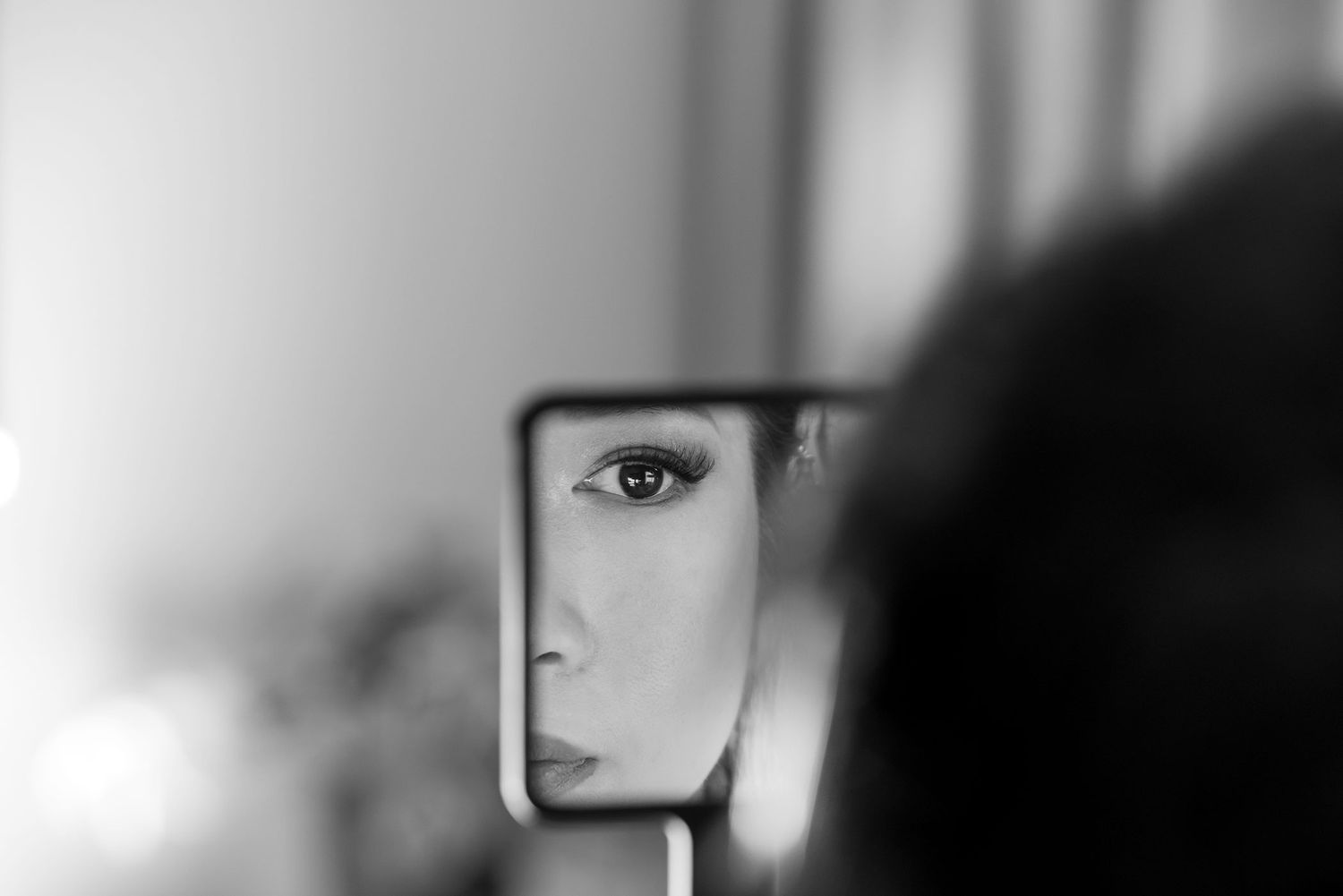 A close-up reflection of a Bride checking her makeup in a mirror with a blurred background during wedding preparations at Quest Albury.