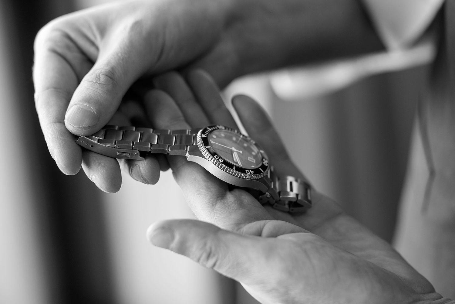 A close-up black and white photo shows a Grooms hands holding his new watch during Wedding Preparations at Quest Albury.