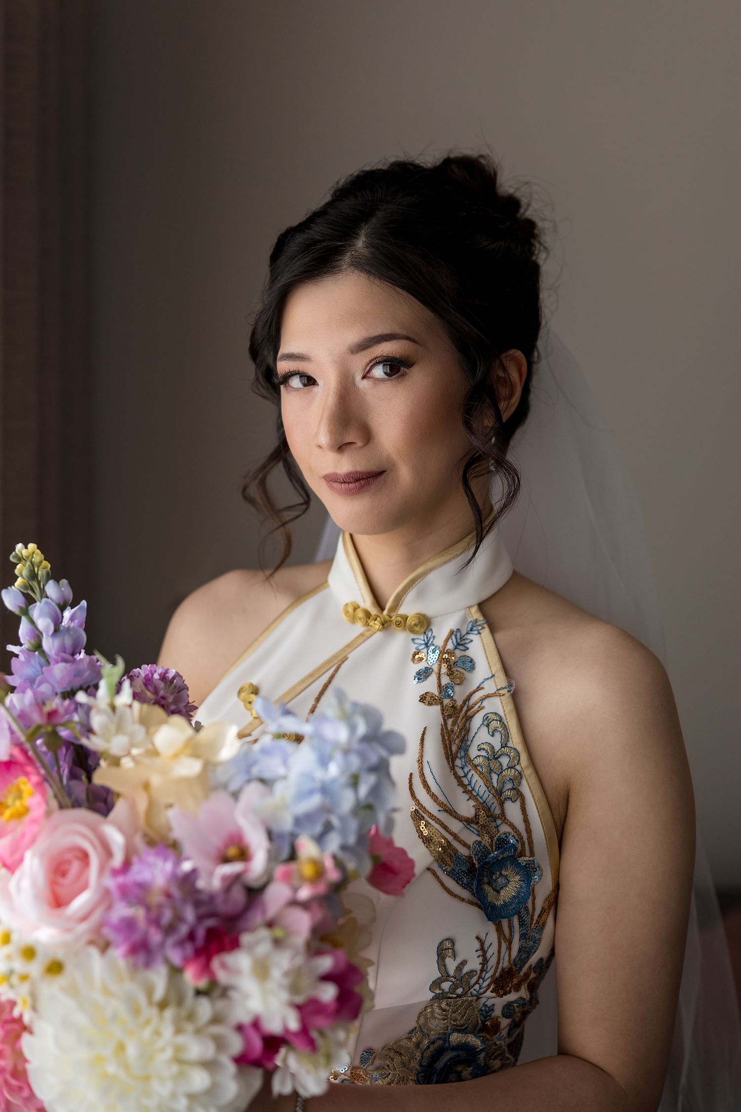 A portait of a Bride in her 'East meets Dress' wedding gown holding a brightly colored floral bouquet during wedding preparation in Albury.