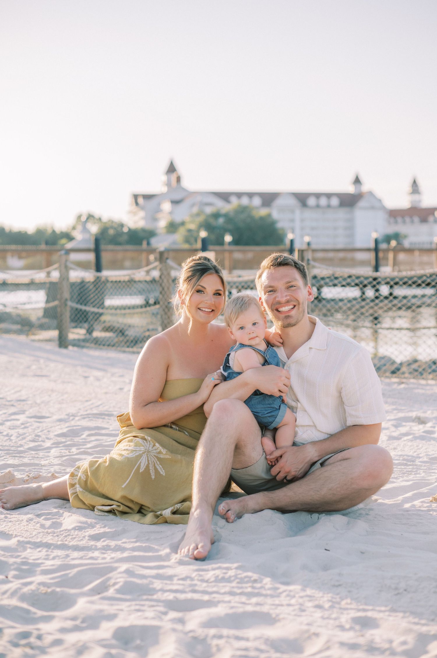 A couple stands together outside on a sunny day near brick buildings and cobblestone pathways.