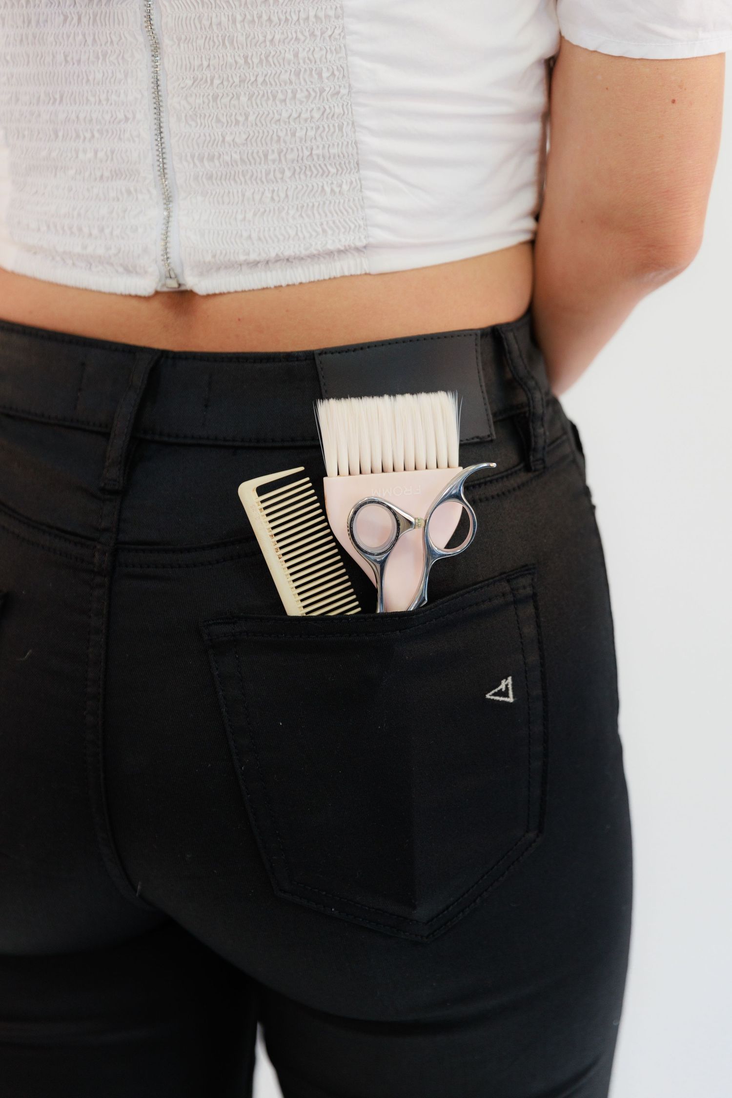 Close up of back pocket with hair combs and scissors showing hair stylist tools.