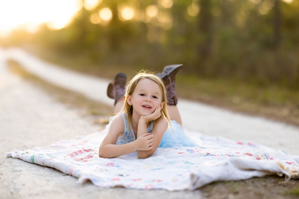 Quilted blanket spread on dirt path during golden hour outdoor photo session.