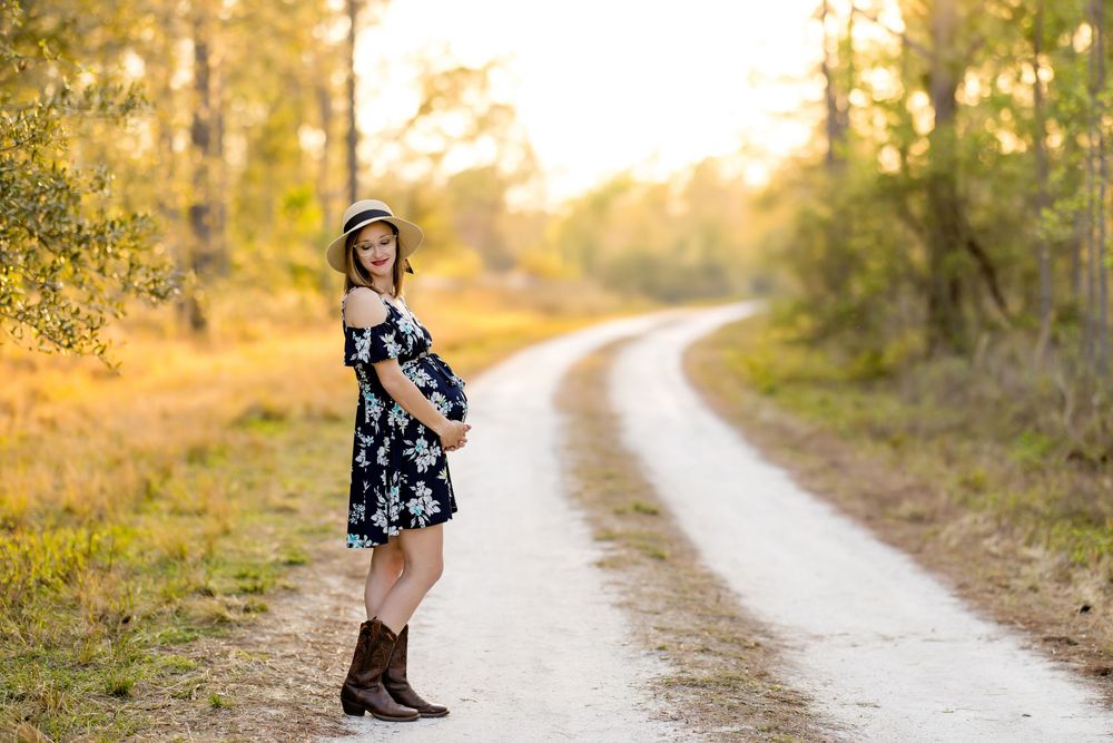 A person in a floral dress and boots poses on a winding path during golden hour. Photos by Tampa Photographer DigitalMyst Photography