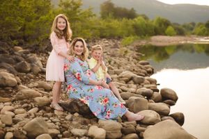 Expecting mother surrounded by family in a soft, glowing maternity photo by Urso Photography.