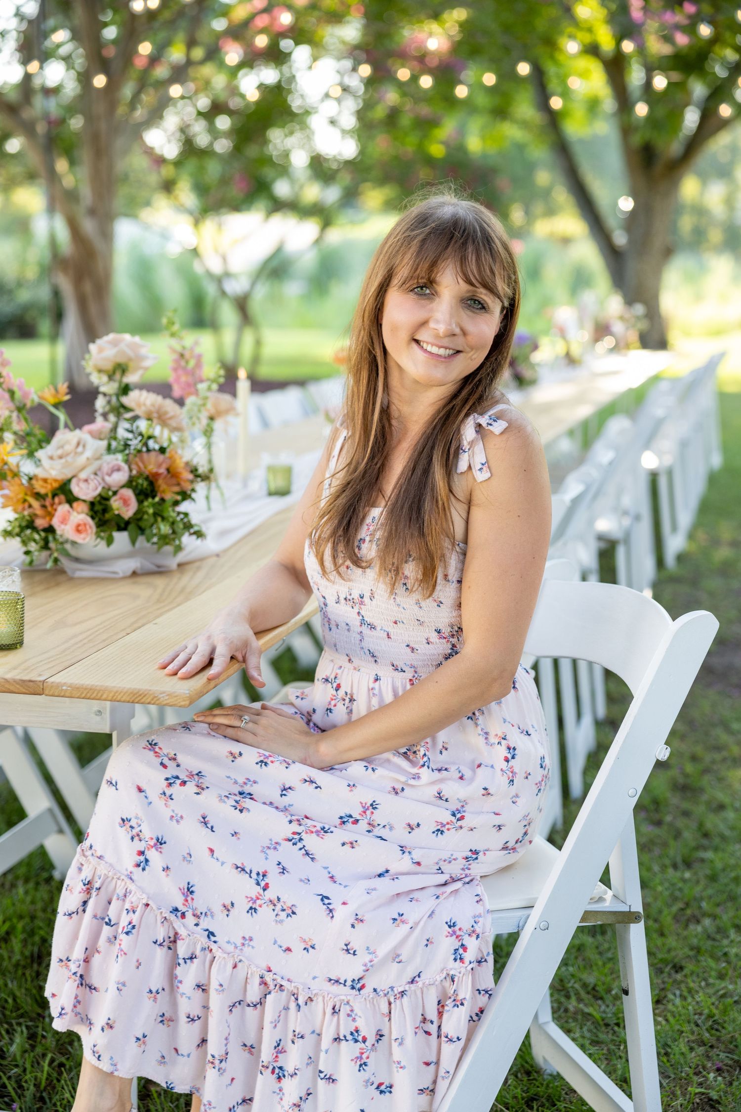 A florist branding photo at an outdoor garden party table with beautiful flower arrangements in the background.