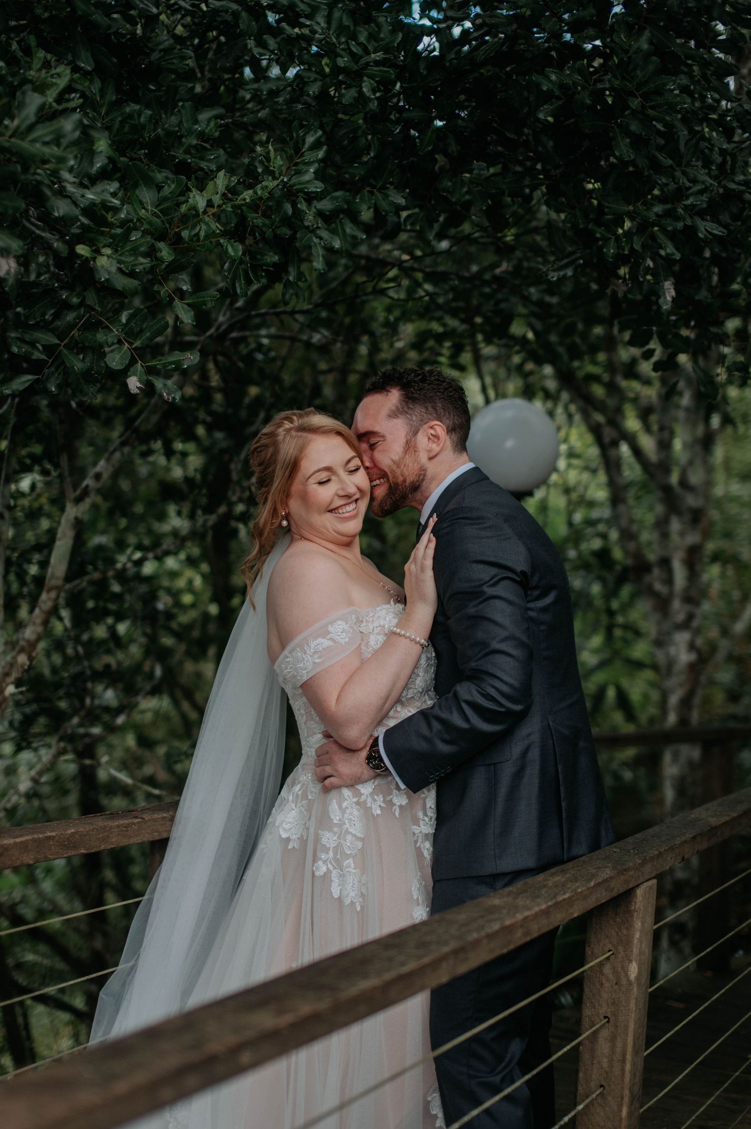 Tender embrace on rustic bridge surrounded by forest canopy.