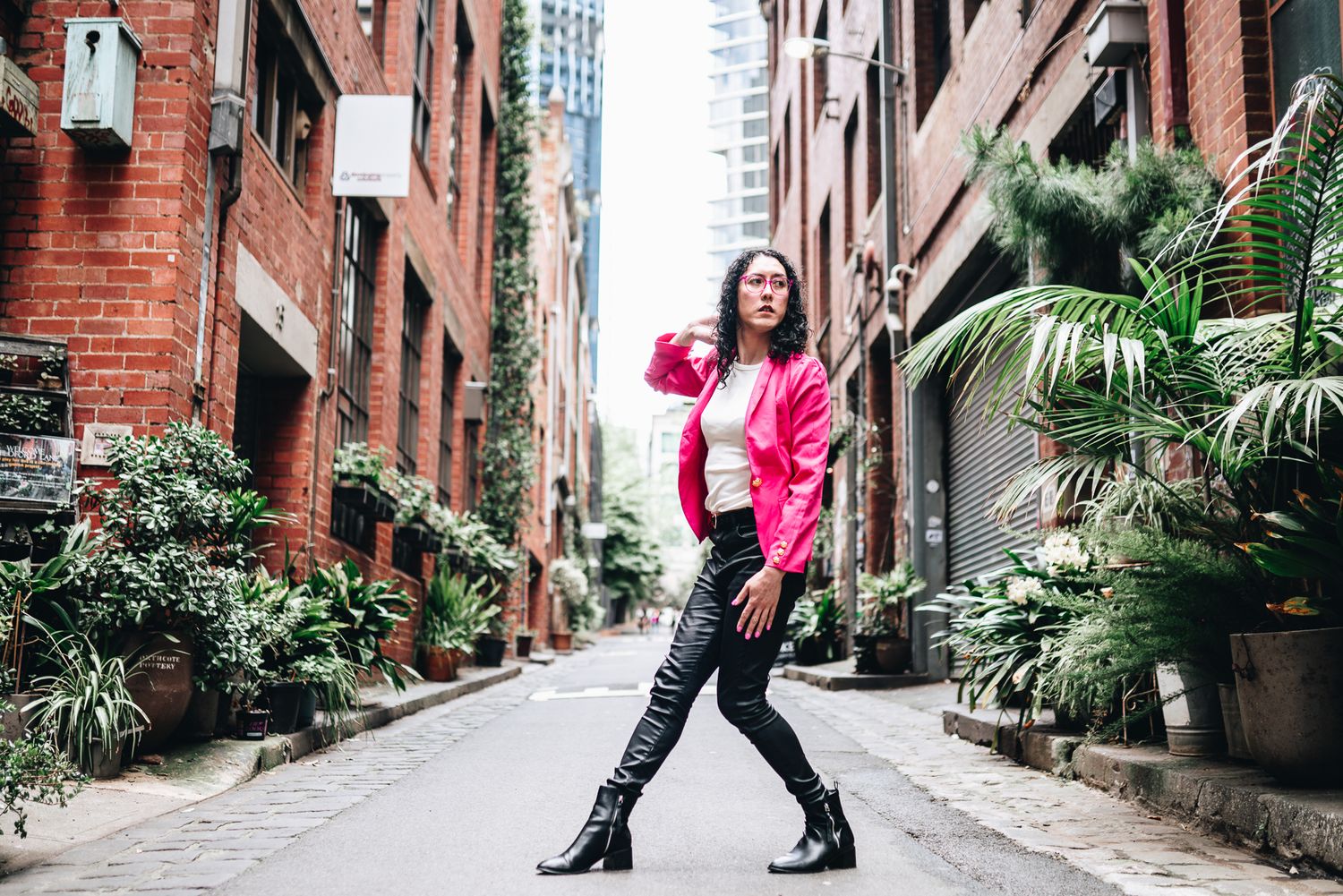 Melbourne lifestyle branding photo of person in pink puffer jacket and boots posing on urban brick-lined laneway—creative street photography