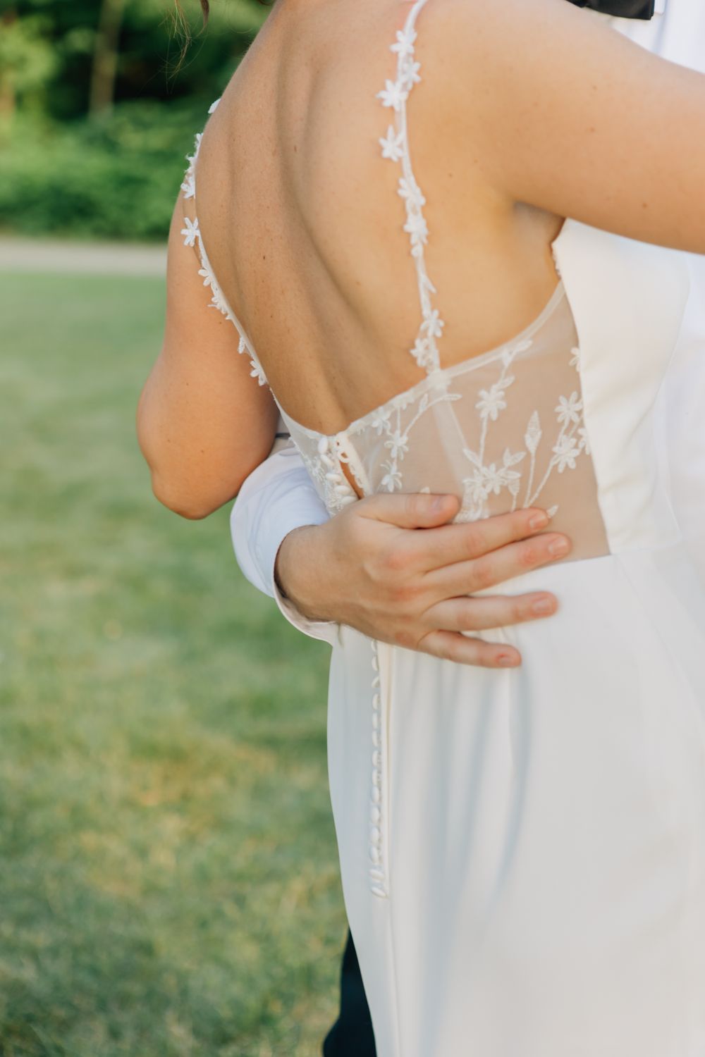 Close-up details of a white wedding dress with delicate lace straps.