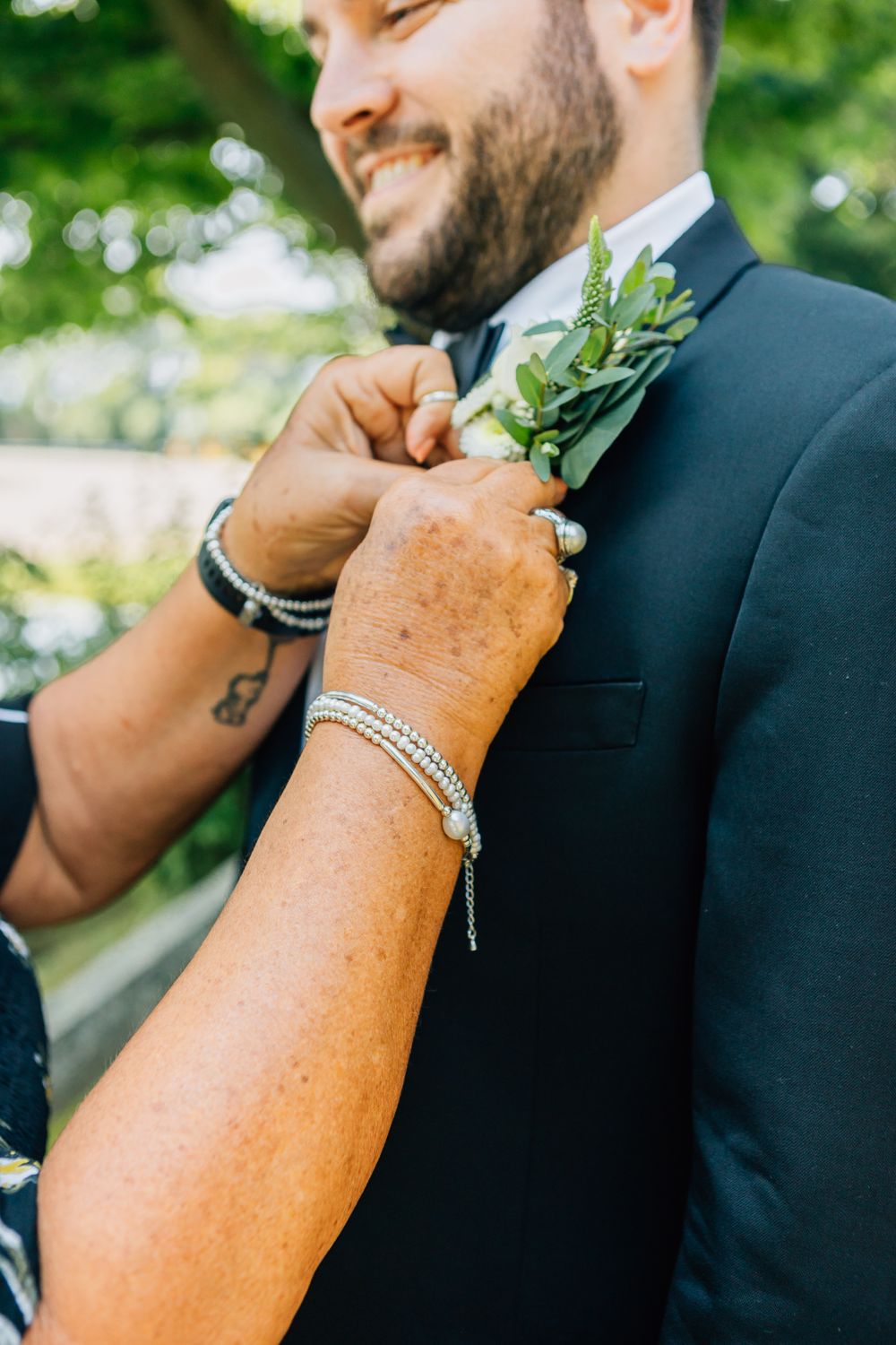 Detail shot of a groom's boutonniere and formal attire during wedding preparations.