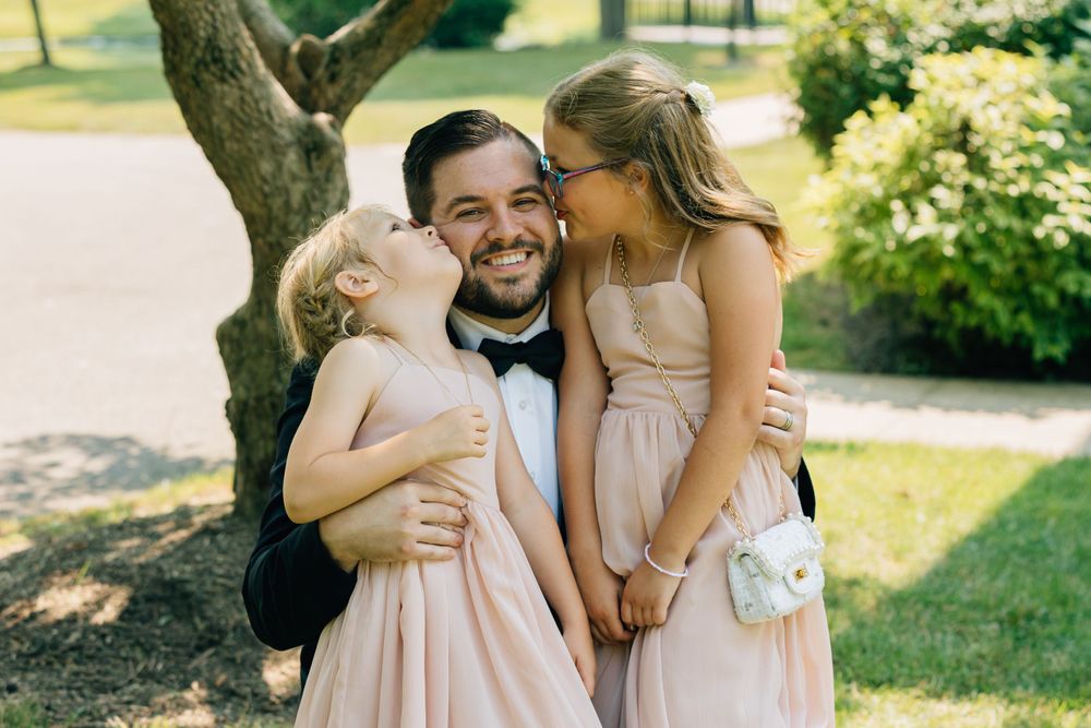 Wedding party members sharing joyful moments outdoors on a sunny day.