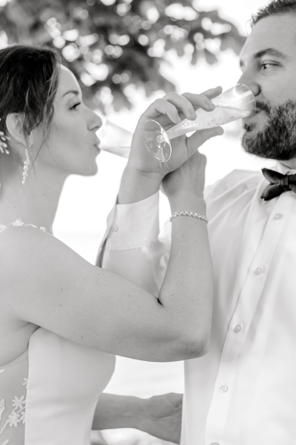 Newlyweds sharing a toast during their wedding celebration in black and white.