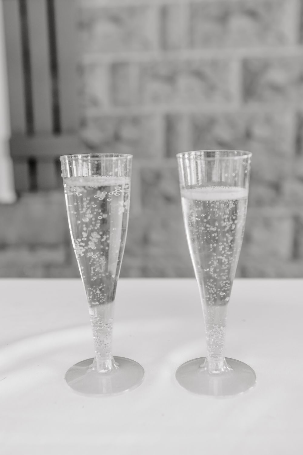 Two crystal champagne glasses on a white tablecloth with elegant place settings.