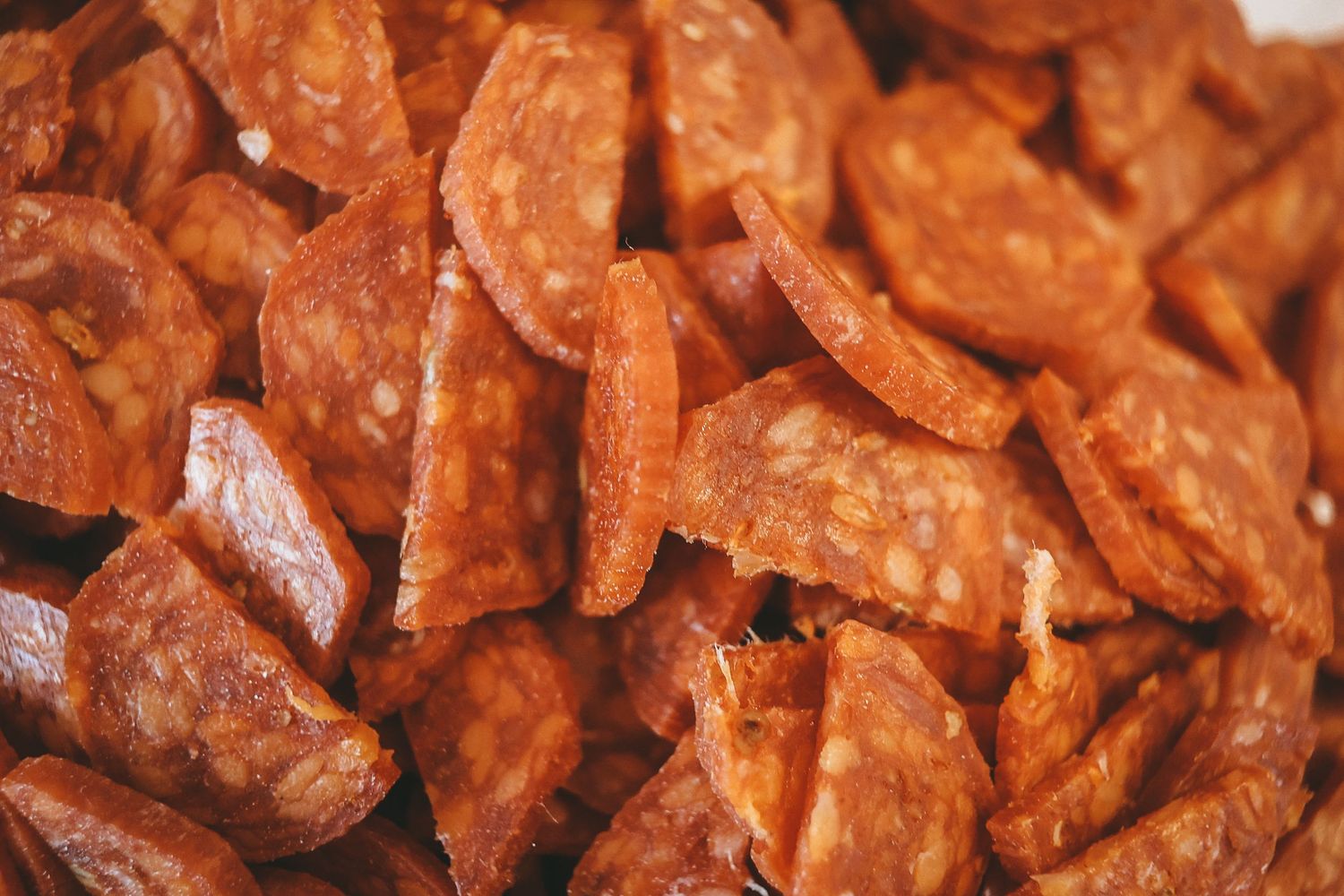 Close up view of sliced chorizo sausage pieces showing their deep reddish color and spicy seasoned texture.