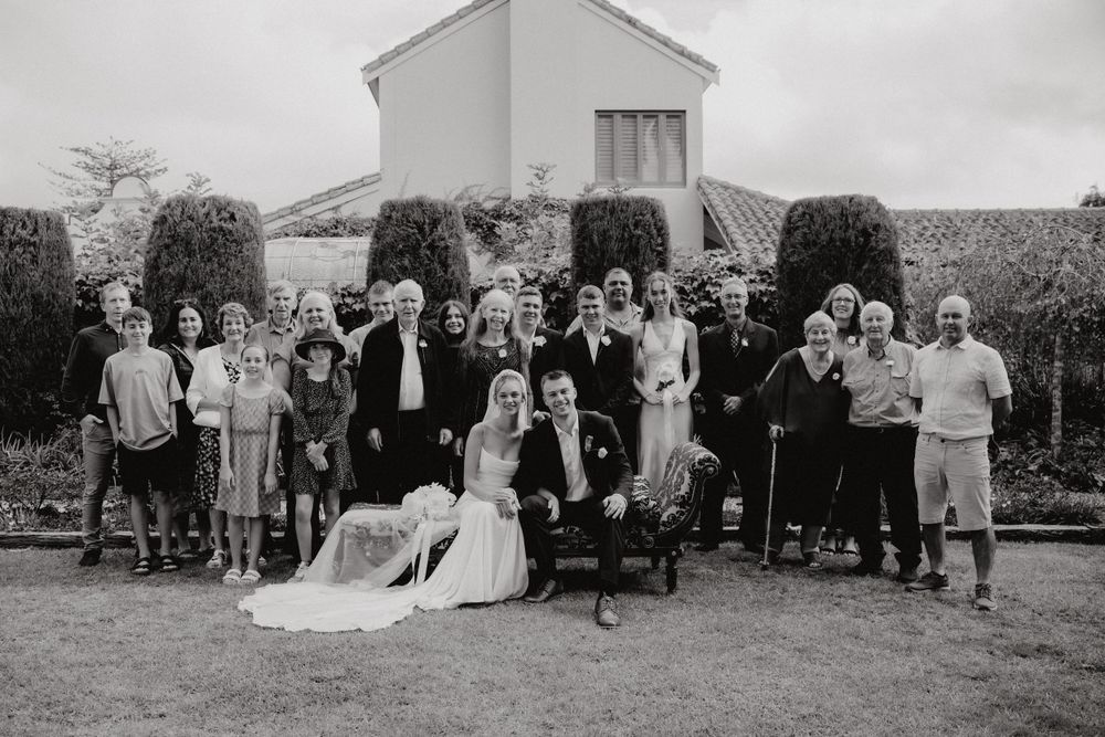 Black and white wedding photo showing a group of guests gathered outside a church building on an overcast day.