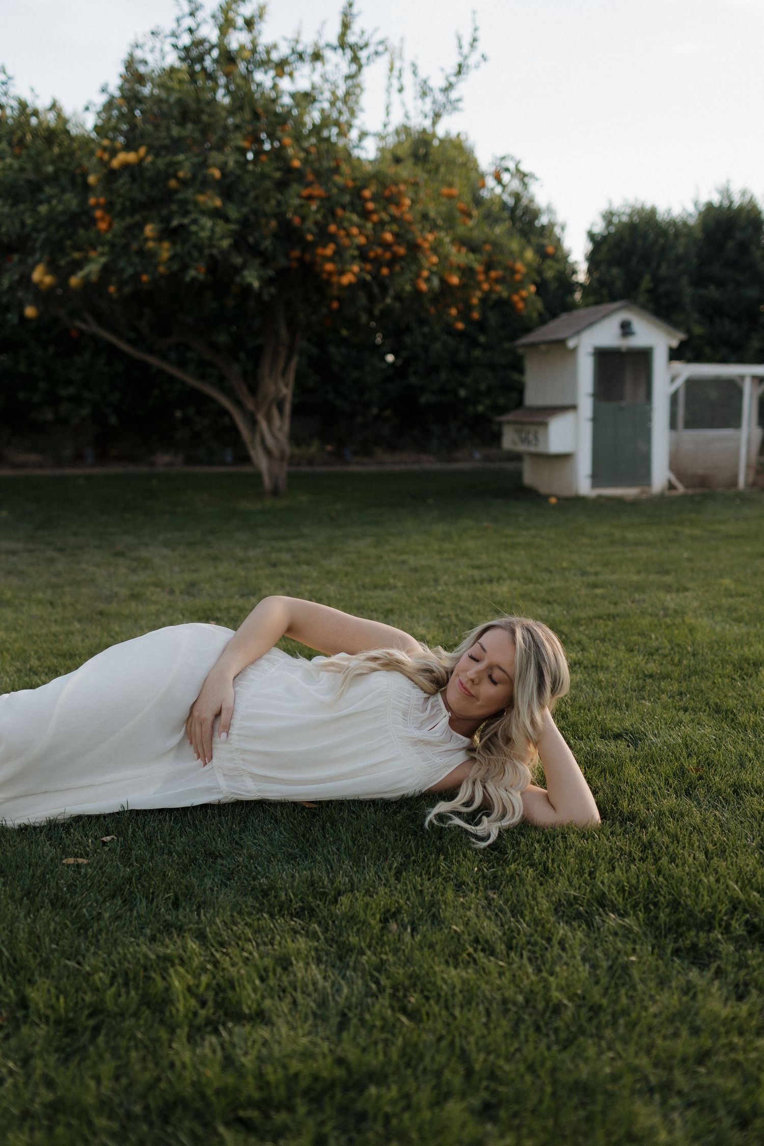 Maternity photography session in a bright bedroom with white curtains and natural lighting.