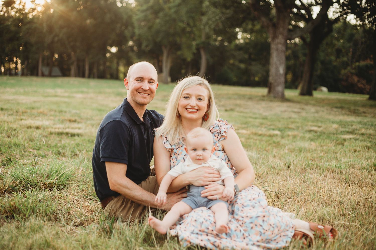 Family sitting together on grass during golden hour sunset photo session.