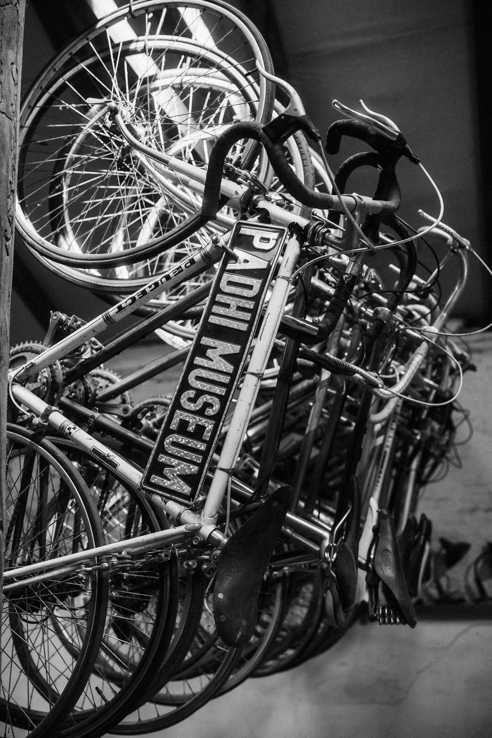 A stack of bicycles piled together with vintage Dutch-style frames shown in black and white.