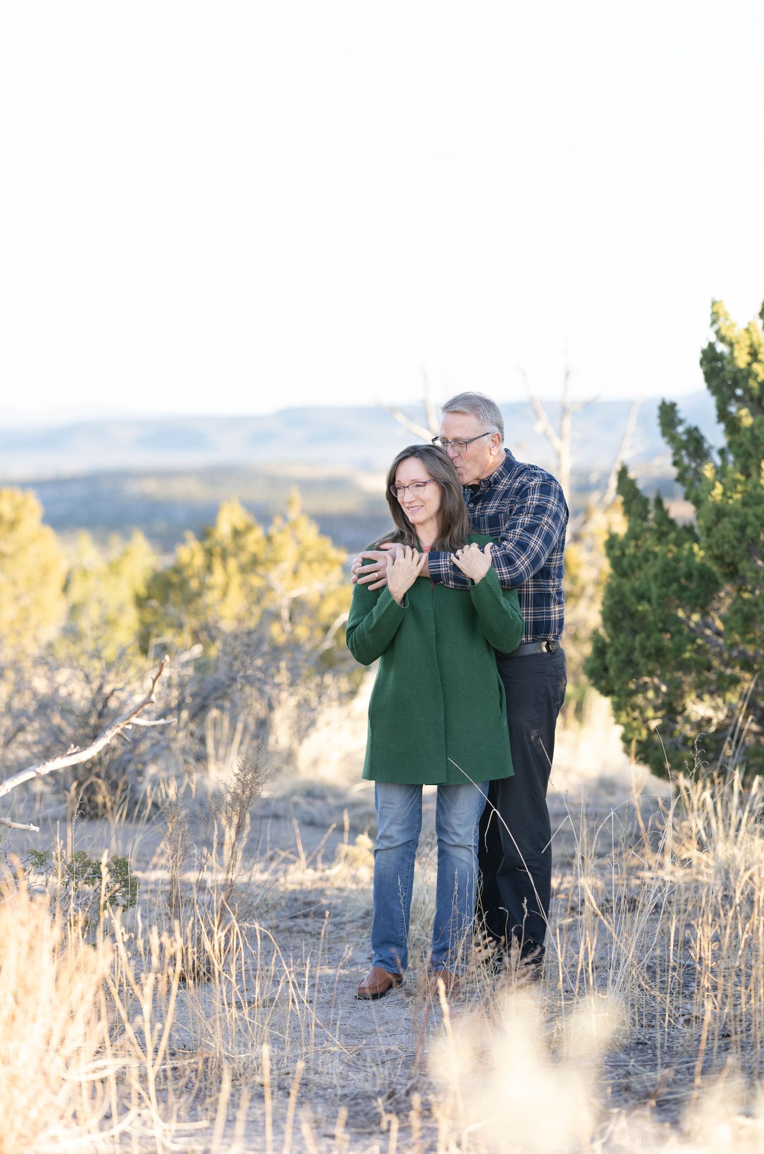 Romantic couple embraces on scenic mountain trail surrounded by autumn foliage.
