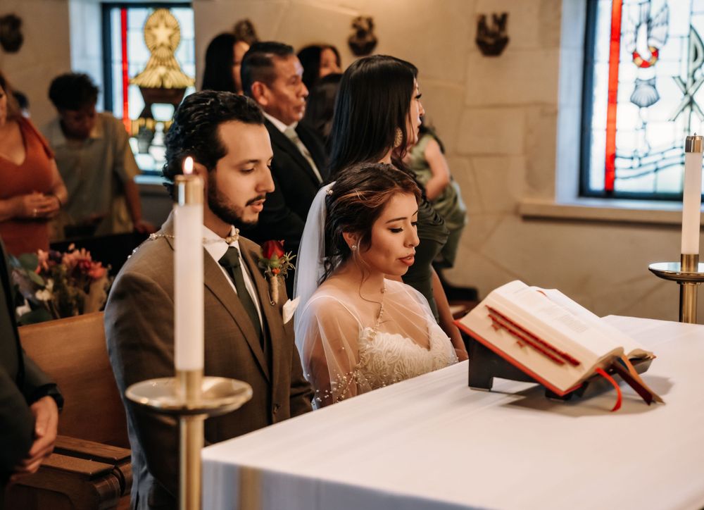 A couple reads from a prayer book during their traditional Catholic church wedding ceremony.