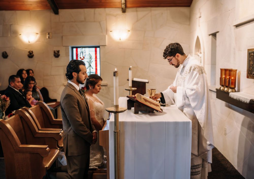 A priest conducts a religious ceremony at an altar while a couple stands before him.