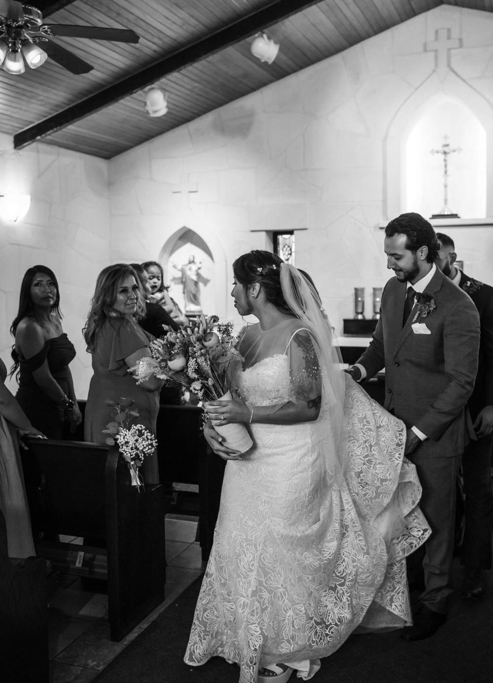A wedding ceremony in progress inside a small chapel with wooden beams and stained glass windows.