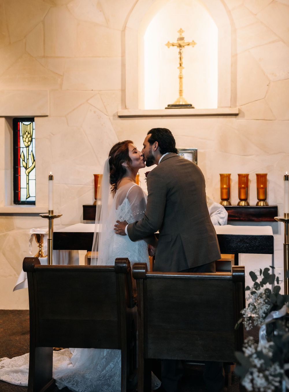 A romantic moment between newlyweds in a church sanctuary with a crucifix visible in the background.