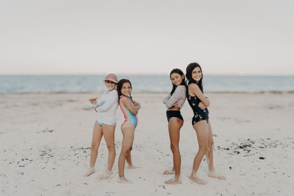 Friends posing together at the beach during sunset.