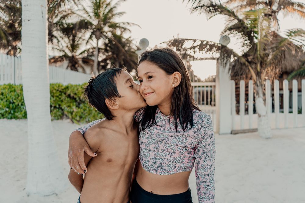 A tender moment shared at a tropical beach with palm trees, showing warmth and connection in natural lighting photoshoot in Puerto Morelos.