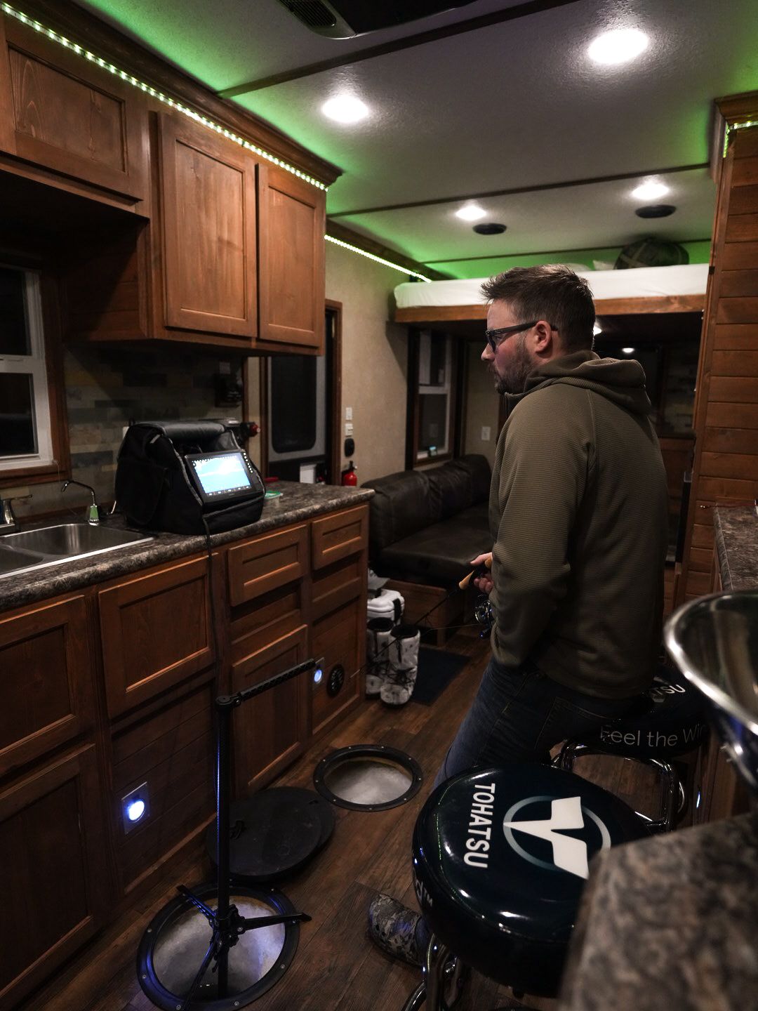 Interior of RV kitchen with wooden cabinets and green LED accent lighting.