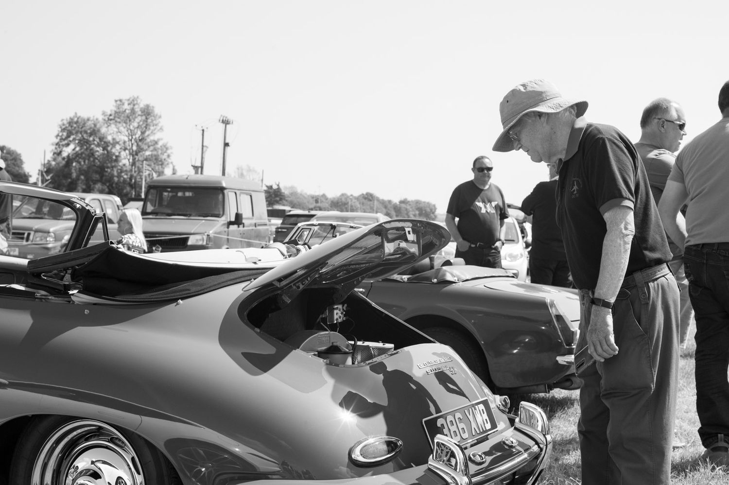 People admiring classic cars at a vintage auto show displayed in black and white photography.