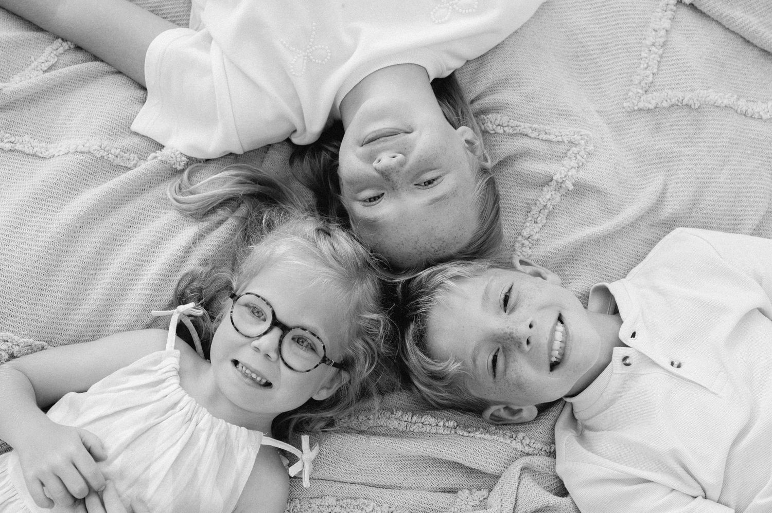 Twee broertjes in communiekleding rennen lachend door het gras tijdens hun fotoshoot.
