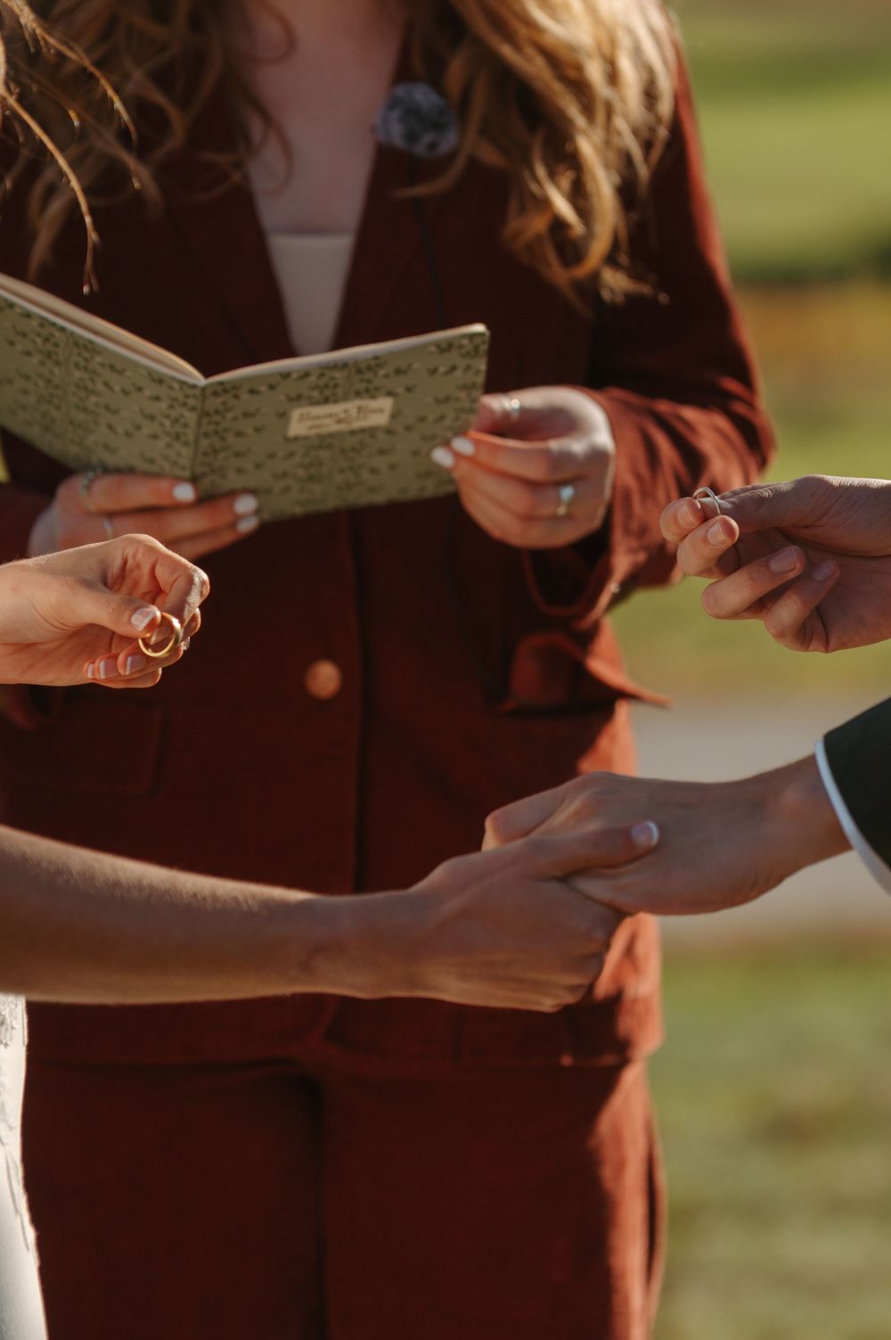 Hands exchanging or passing paper notes or cards in warm sunlight outdoors.