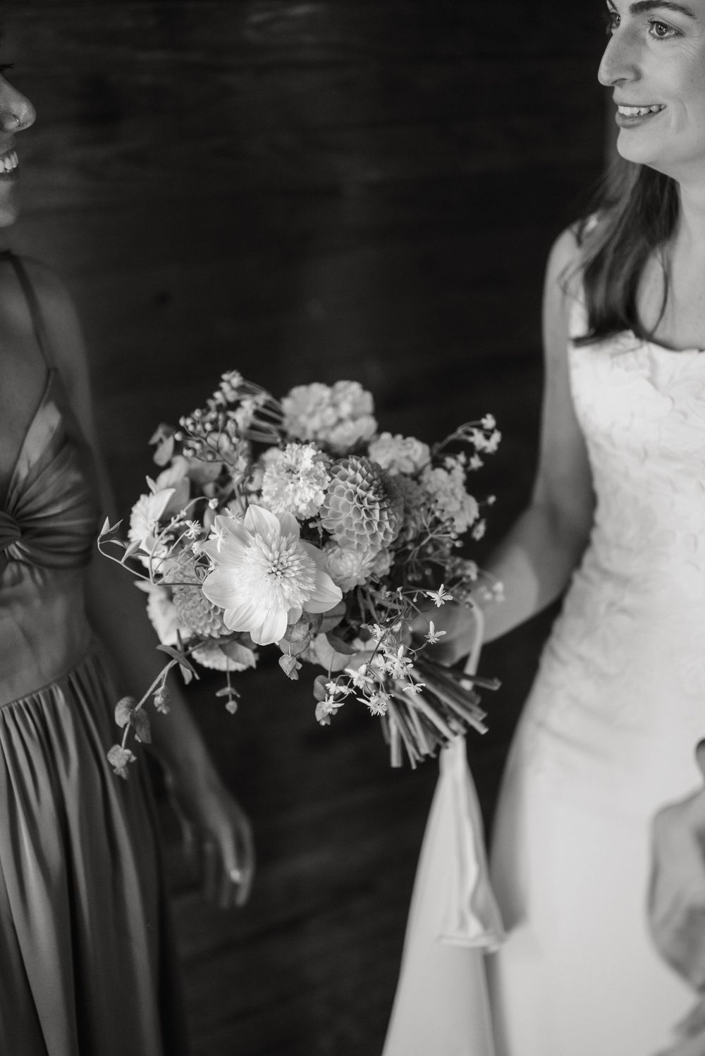 Black and white wedding photo showing elegant bouquets with white flowers and dark bridesmaid dresses.