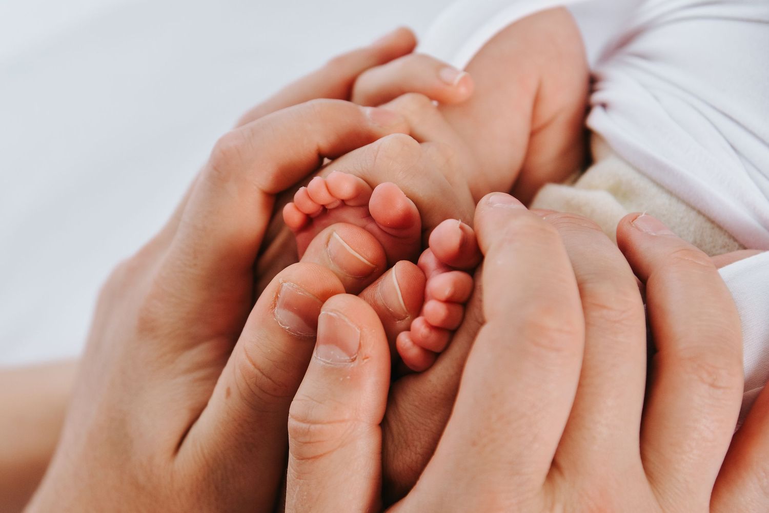 Close-up shot of tiny baby feet being gently held in adult hands.