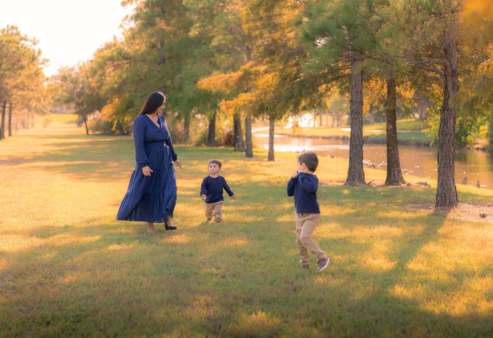 Family enjoying a golden autumn afternoon in a park with sunlight filtering through trees. Houston, TX