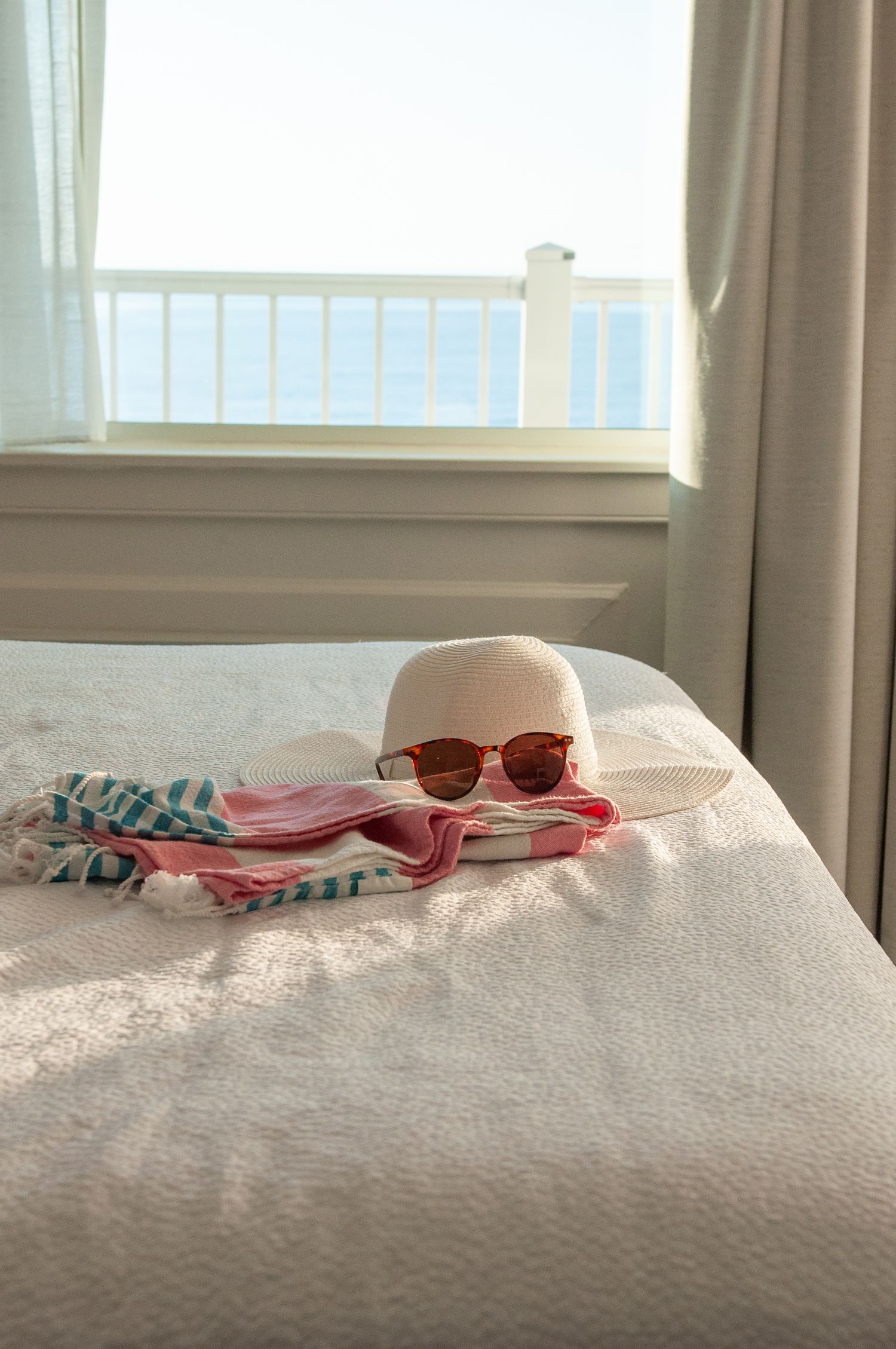 Lifestyle shot of glasses hat and beach towel on the bed in an oceanfront hotel