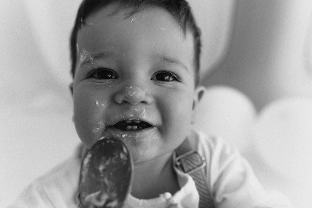 Black and white photo of a smiling baby enjoying an ice cream cone, showing pure joy and delight.