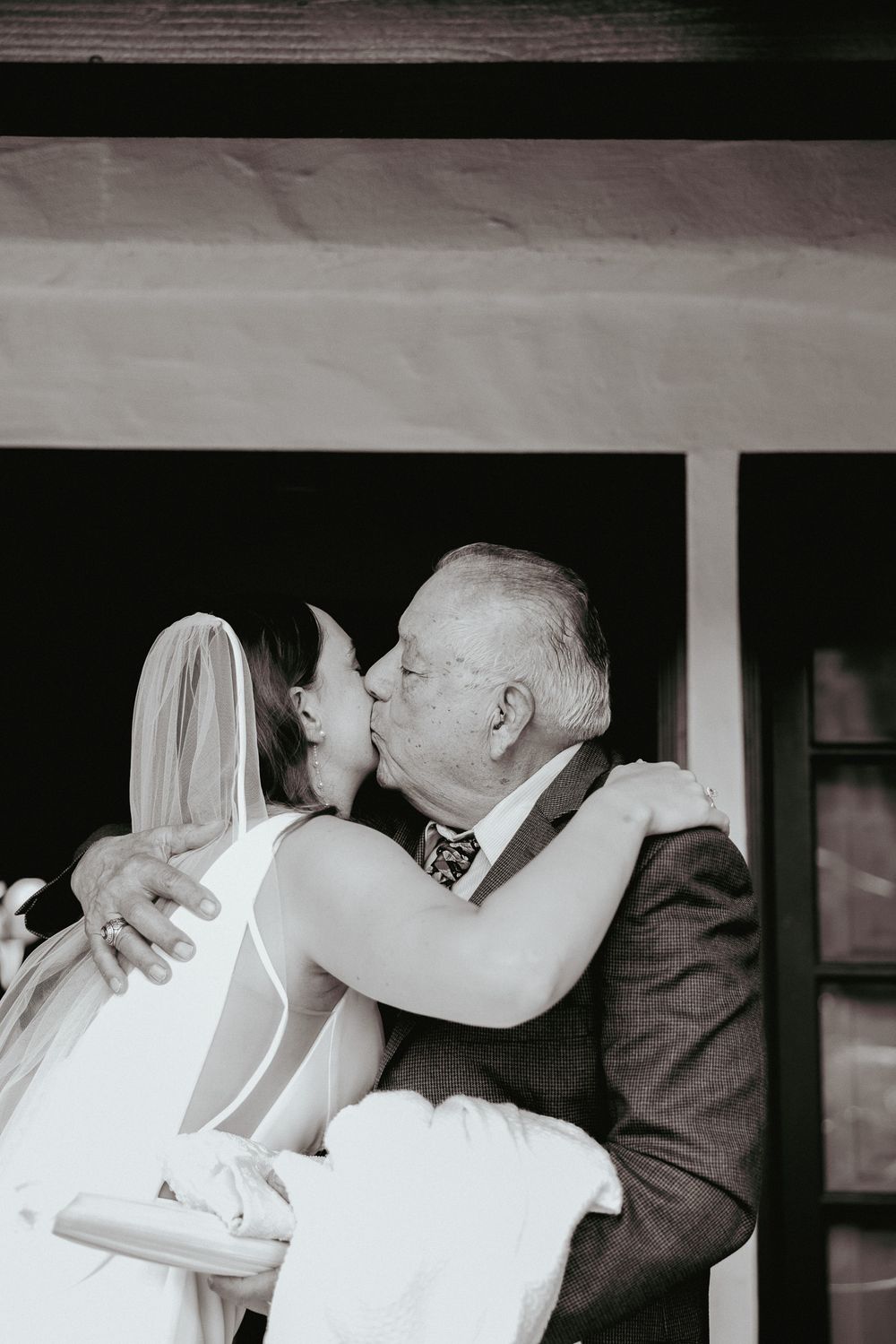 Emotional black and white photo of a tender moment between a bride and an older gentleman.