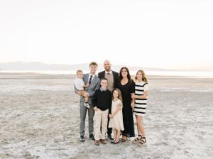 A group poses together on a sandy beach during golden hour.