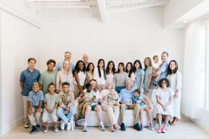 Large group portrait in white room wearing coordinated blue and white outfits.