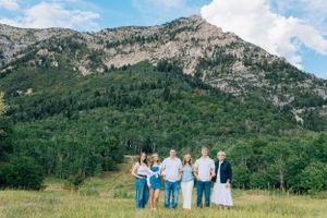 Group walking together in mountain meadow with dramatic rocky peaks in background.