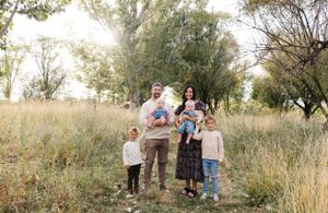 A group poses in a sunlit meadow with trees during golden hour.