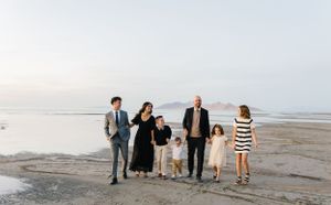 A group stands together on a misty beach at sunset wearing casual attire.