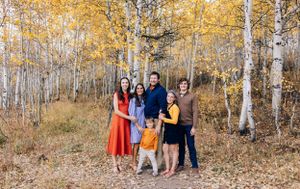 A group stands among golden aspen trees during autumn in a forest setting.